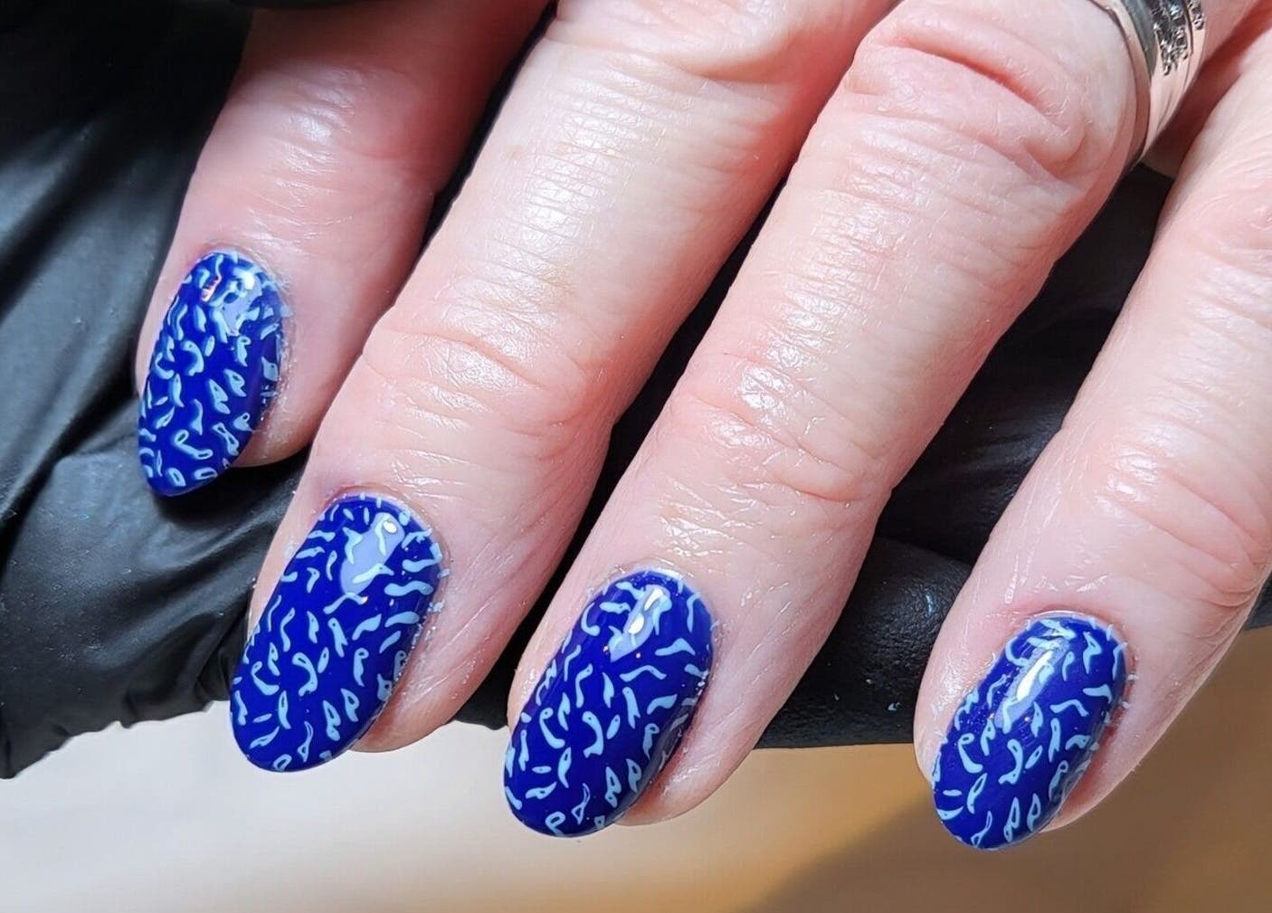 Close-up of blue patterned nails at Coco Beauty, Belper, England, GB. Stylish nail art treatment.