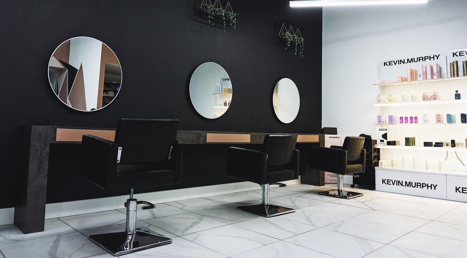 Modern salon interior at Black House Salon, Huddersfield, England, GB, featuring sleek chairs and mirrors.