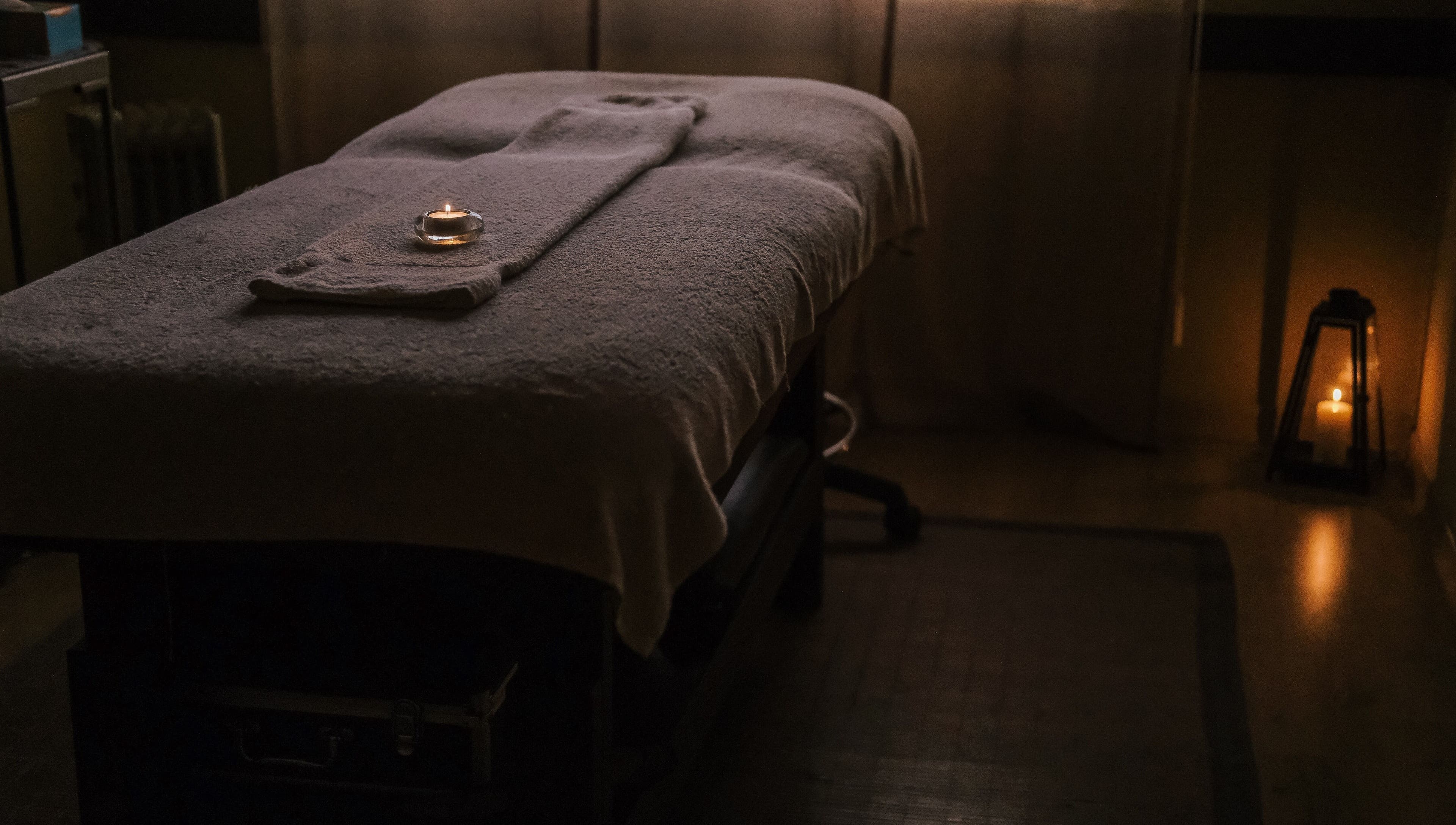 Sala de massagem no Zen Spa, Tomar, Santarém, PT, com luz suave e vela acesa.