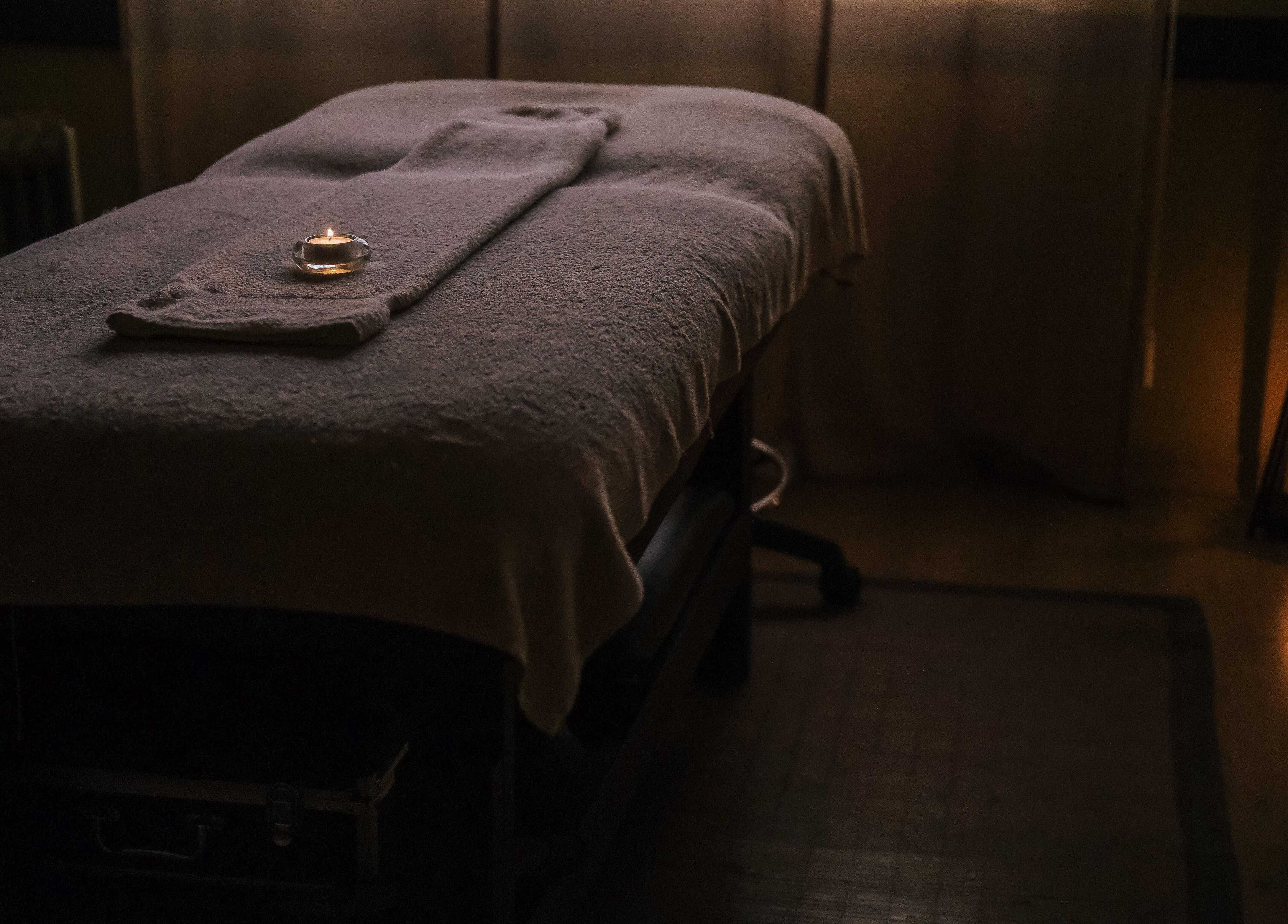 Sala de massagem no Zen Spa, Tomar, Santarém, PT, com luz suave e vela acesa.