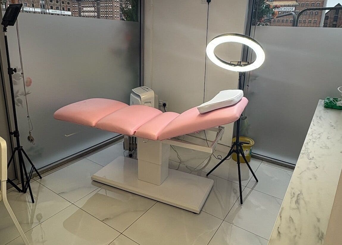 Sleek treatment room at Abbie Doctor Aesthetics, Gloucester, England. Features chic pink chair and modern lighting.