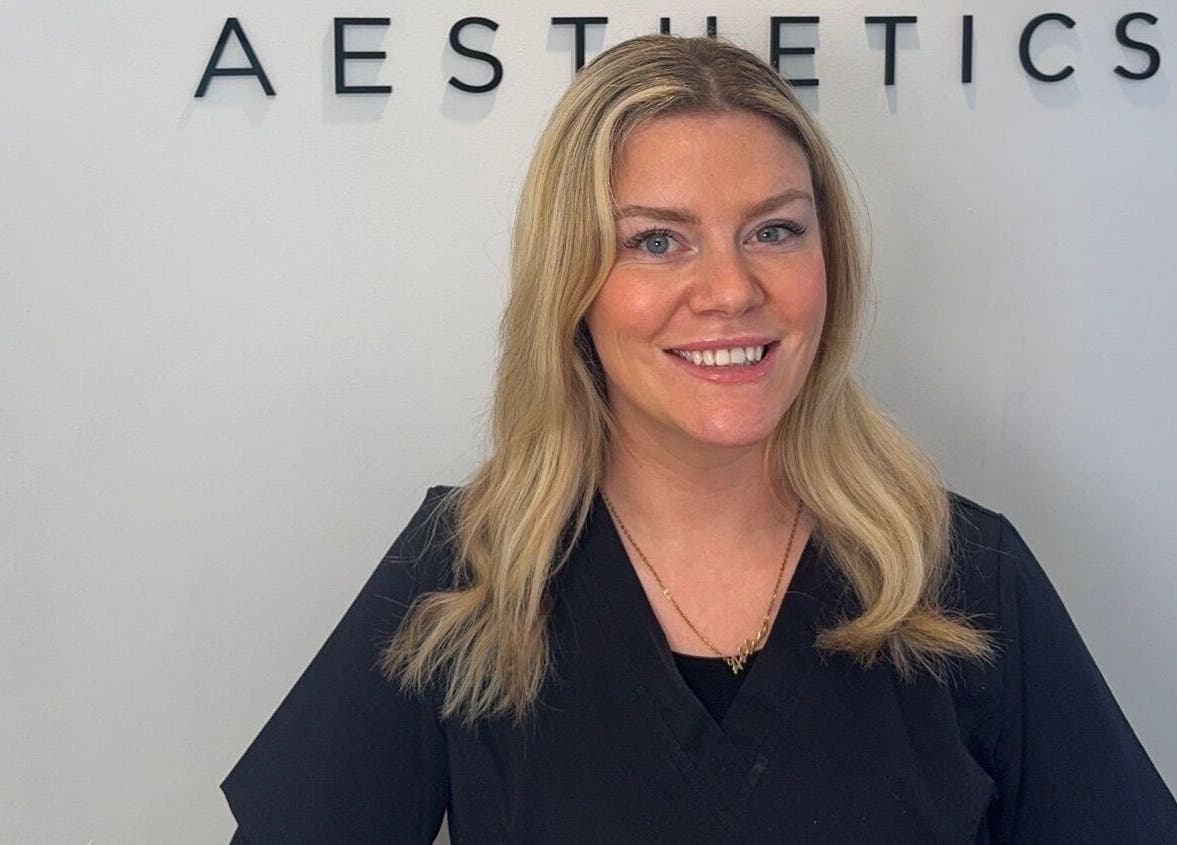 Professional at Abbie Doctor Aesthetics in Gloucester, England, GB, smiling in front of a sign.