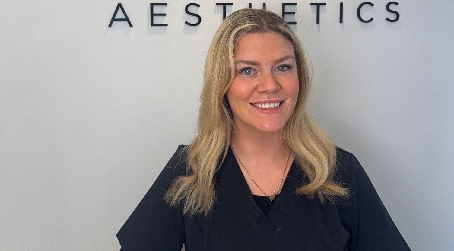 Professional at Abbie Doctor Aesthetics in Gloucester, England, GB, smiling in front of a sign.