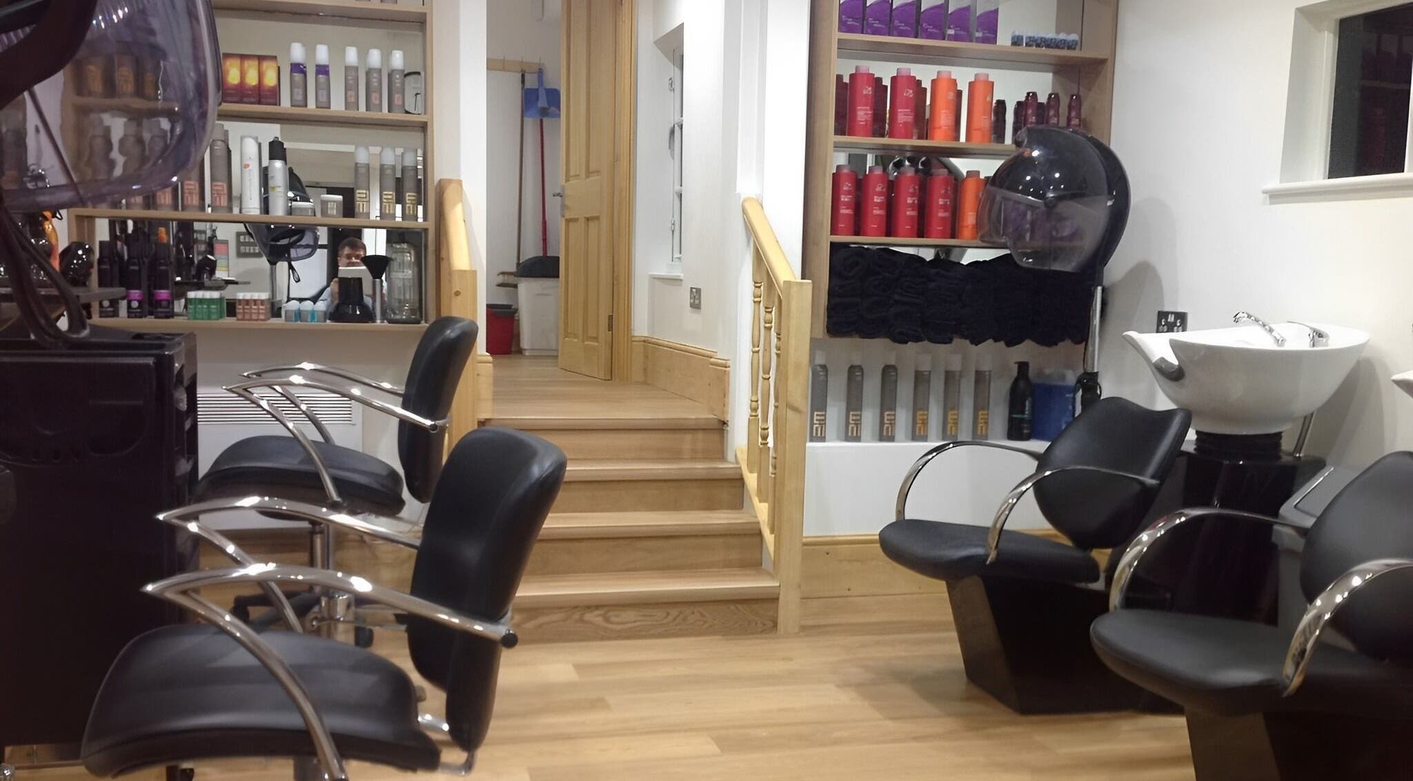 Modern interior of Forge Hair Salon in Rotherfield, England, GB with sleek chairs and product shelves.
