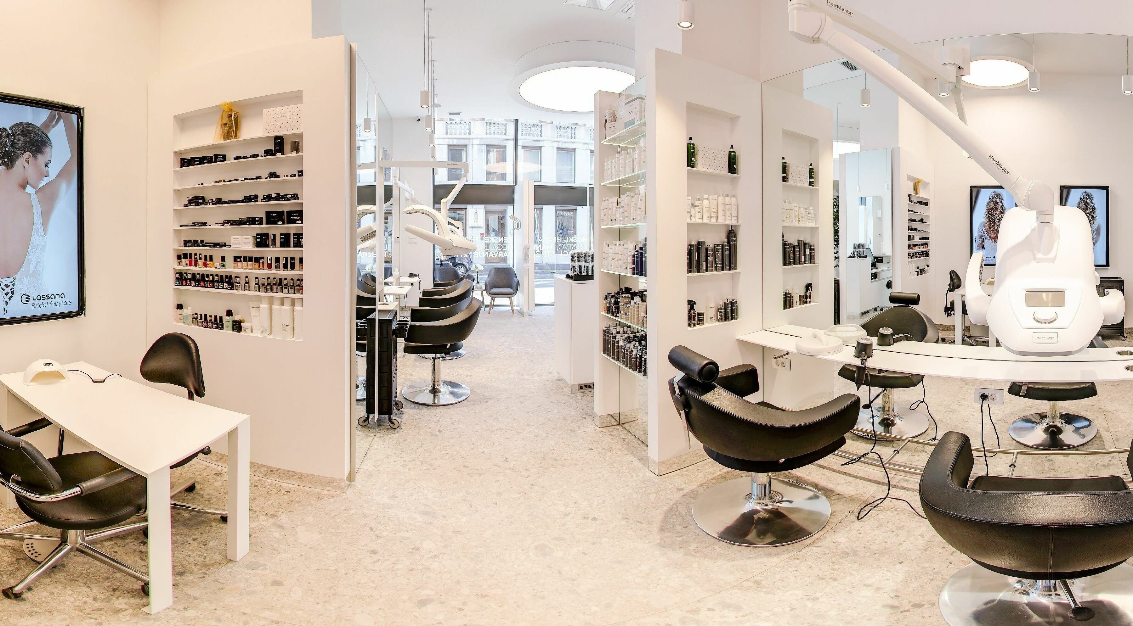 Sodobna notranjost Lassana Frizerski Salon - Miklošičeva 40, Ljubljana. Svetel prostor s stiliškimi stoli in izdelki.