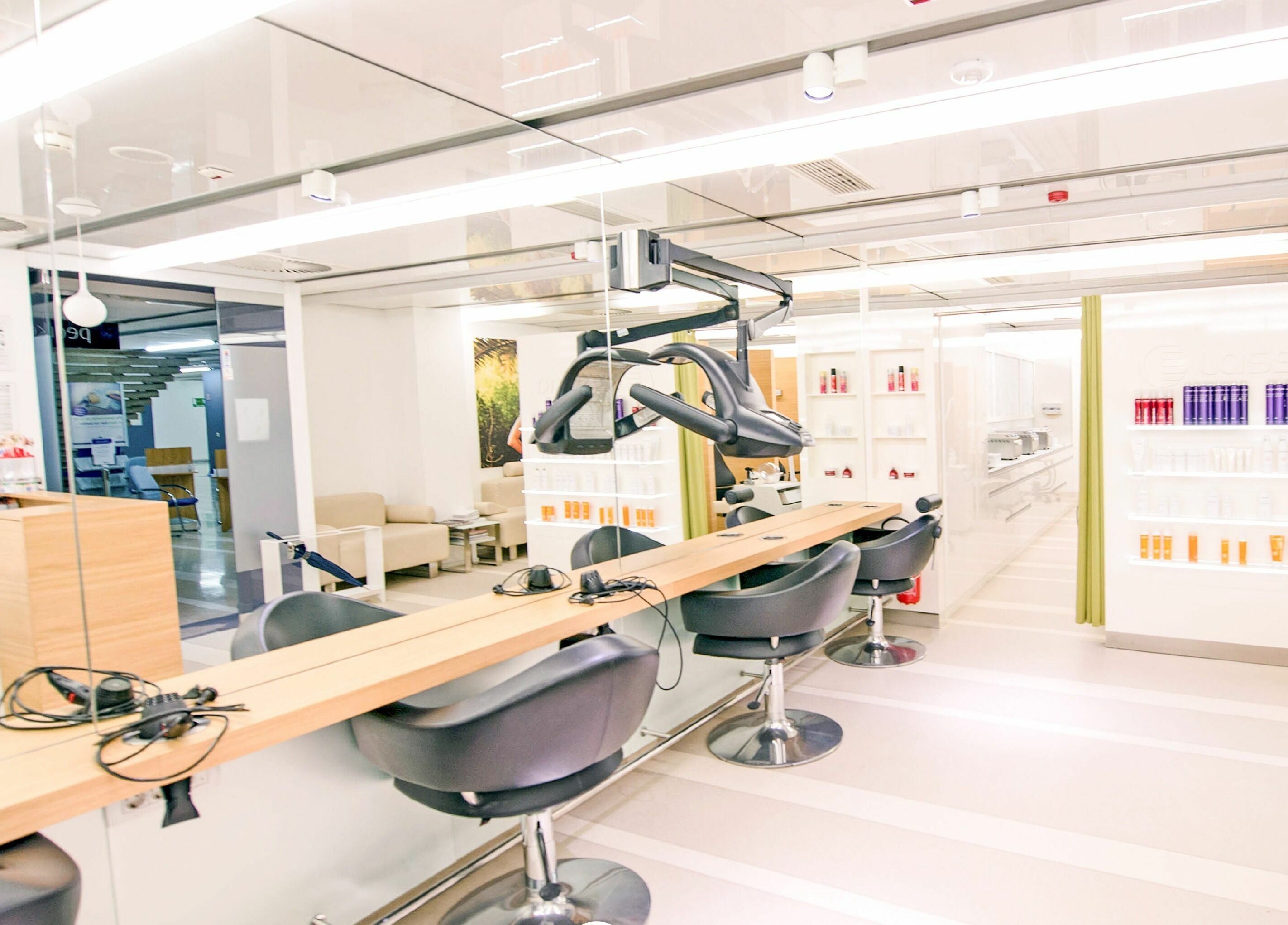 Notranjost Lassana Frizerski in Kozmetični Salon - Zaloška 7, Ljubljana, Ljubljana, SI z elegantnimi stoli in osvetlitvijo.