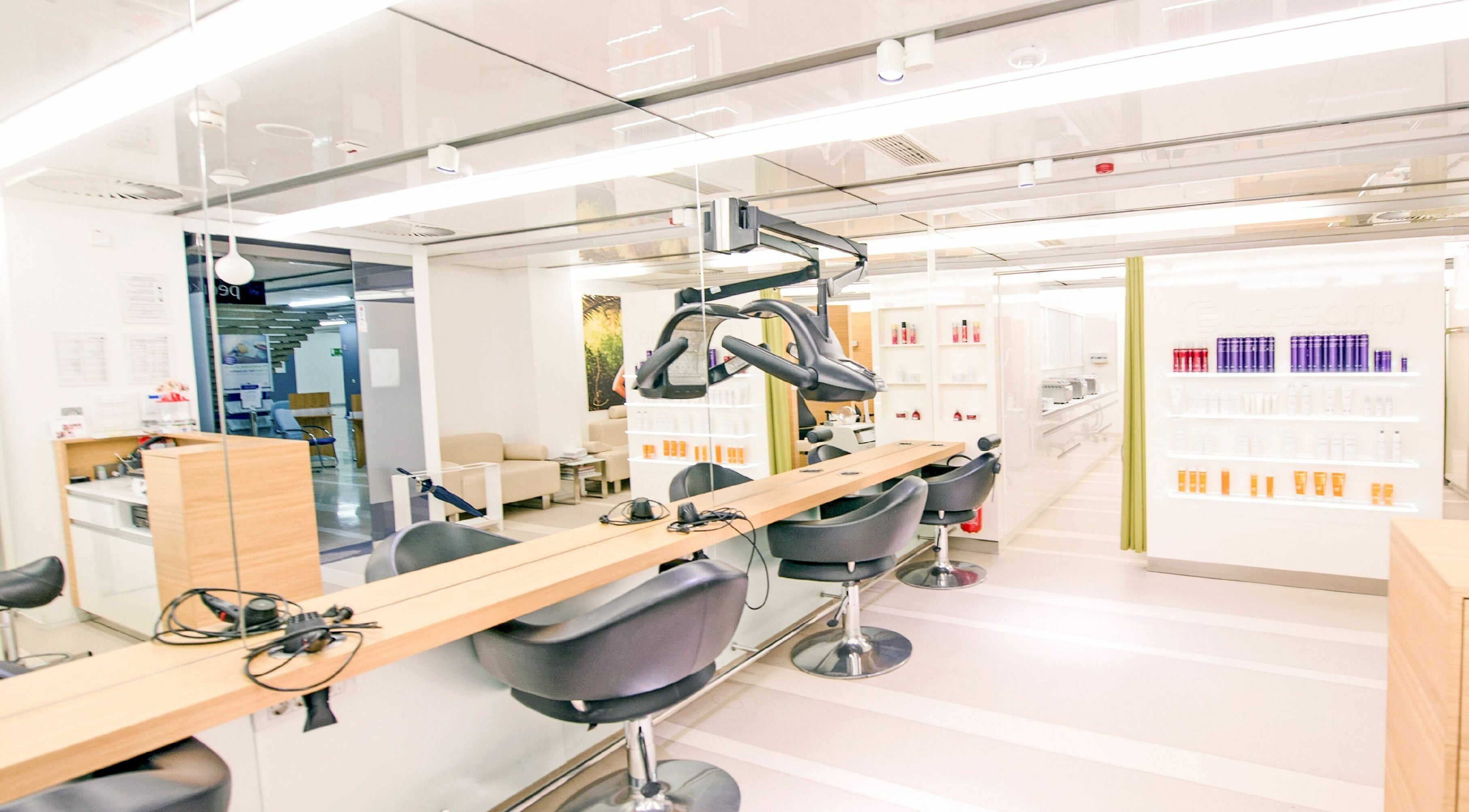 Notranjost Lassana Frizerski in Kozmetični Salon - Zaloška 7, Ljubljana, Ljubljana, SI z elegantnimi stoli in osvetlitvijo.