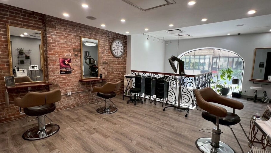 Salon interior at Momotaro in New York, New York, US featuring stylish chairs and exposed brick walls.