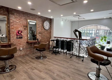 Salon interior at Momotaro in New York, New York, US featuring stylish chairs and exposed brick walls.