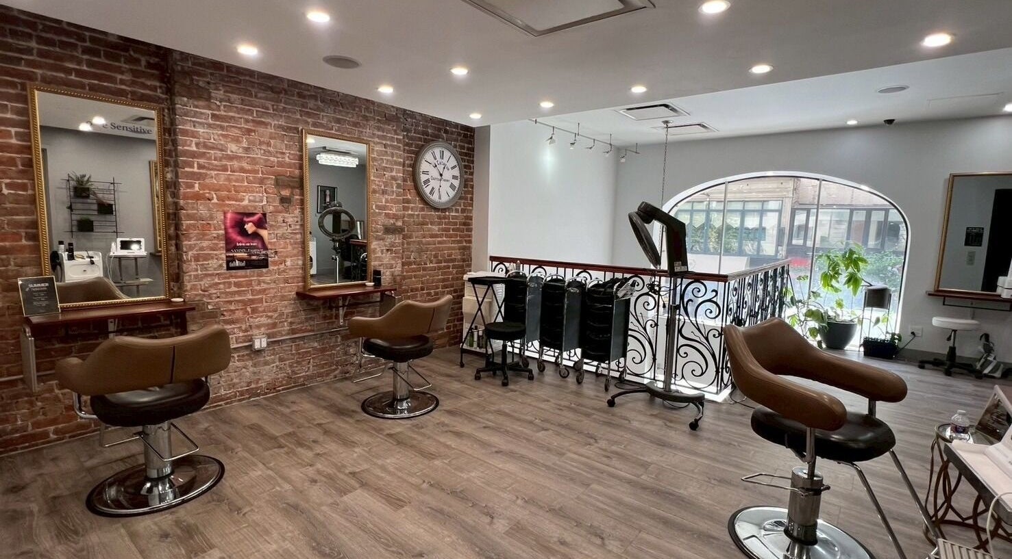 Salon interior at Momotaro in New York, New York, US featuring stylish chairs and exposed brick walls.