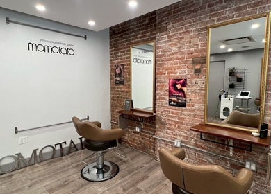 Modern interior of Momotaro salon in New York, New York, US, featuring stylish chairs and exposed brick walls.