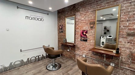Modern interior of Momotaro salon in New York, New York, US, featuring stylish chairs and exposed brick walls.