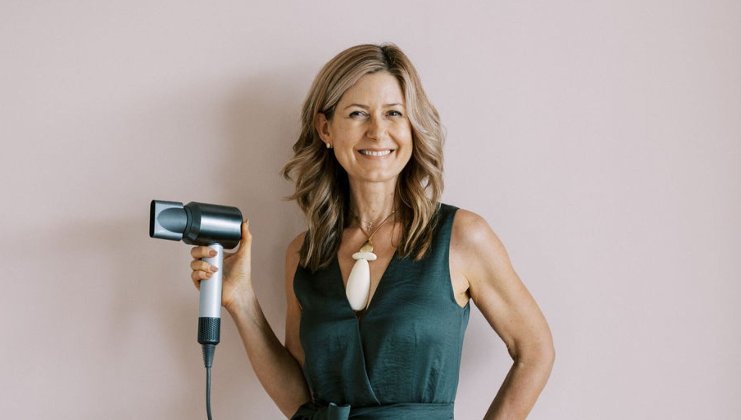 Smiling hair stylist holding hairdryer at Bardon Hair Design, Bardon, Queensland, AU.