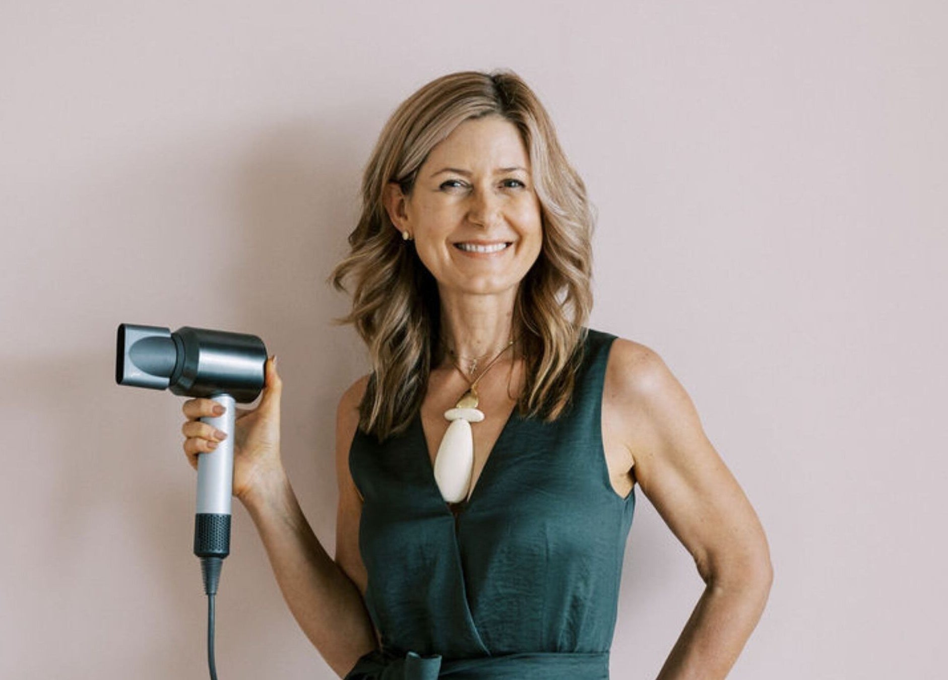 Smiling hair stylist holding hairdryer at Bardon Hair Design, Bardon, Queensland, AU.