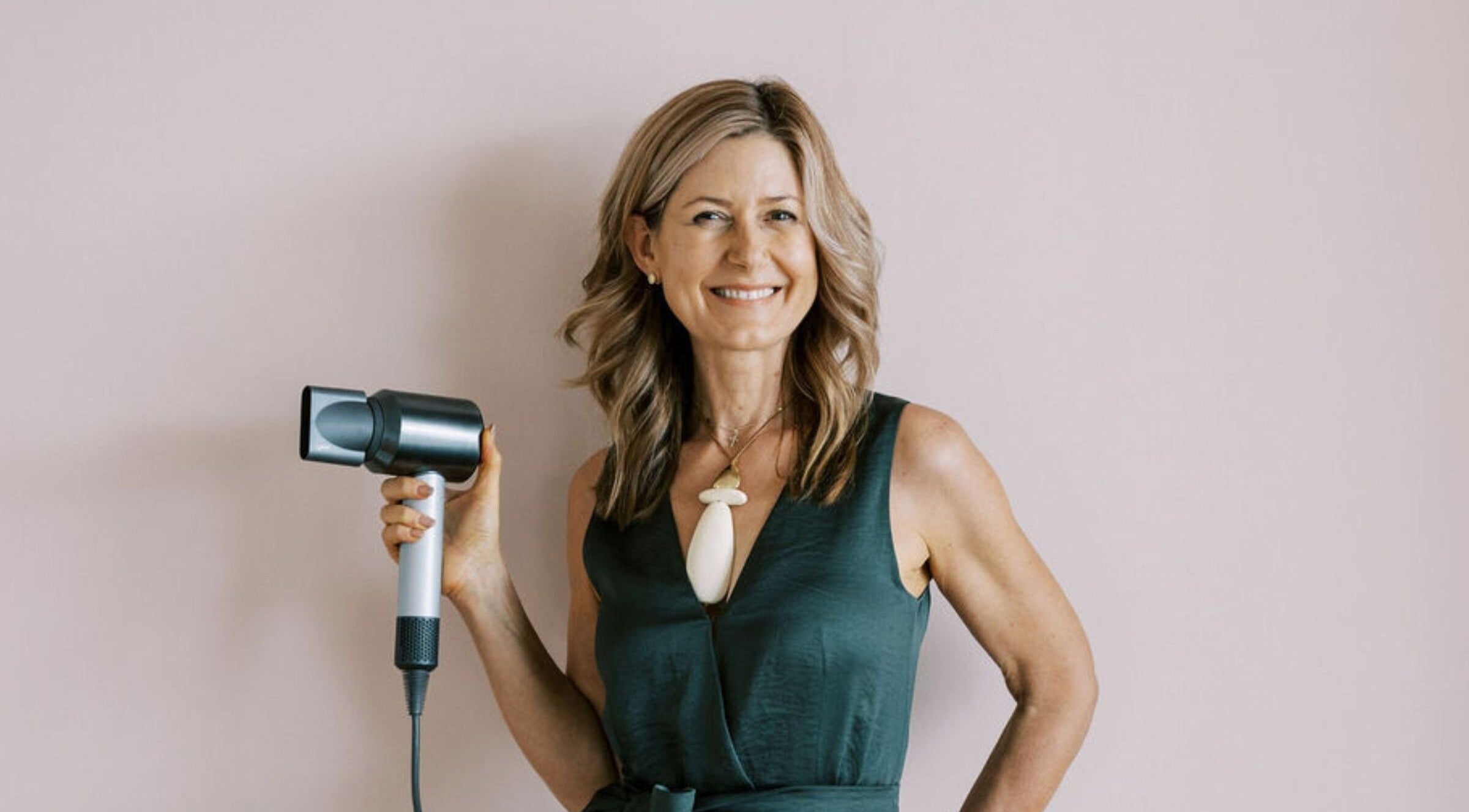 Smiling hair stylist holding hairdryer at Bardon Hair Design, Bardon, Queensland, AU.