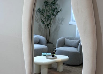 Stylish lounge at Lilynailsmater Carle Place, New York, US with mirror and modern furniture.