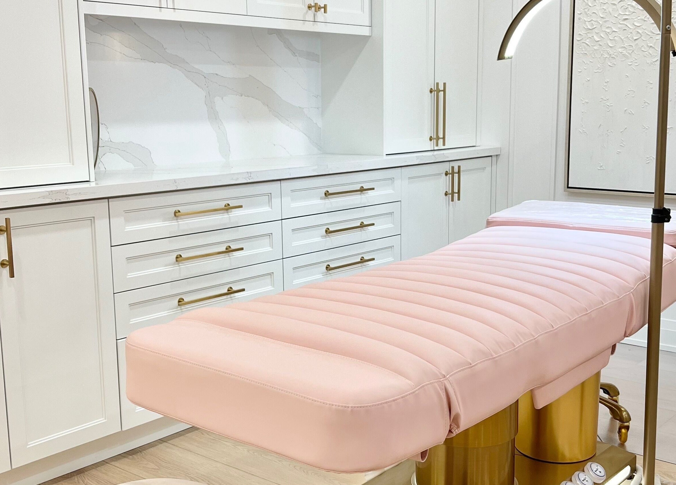 Elegant treatment room at Lash Layer and Brow Boutique, Pickering, Ontario, CA with plush pink bed and gold accents.