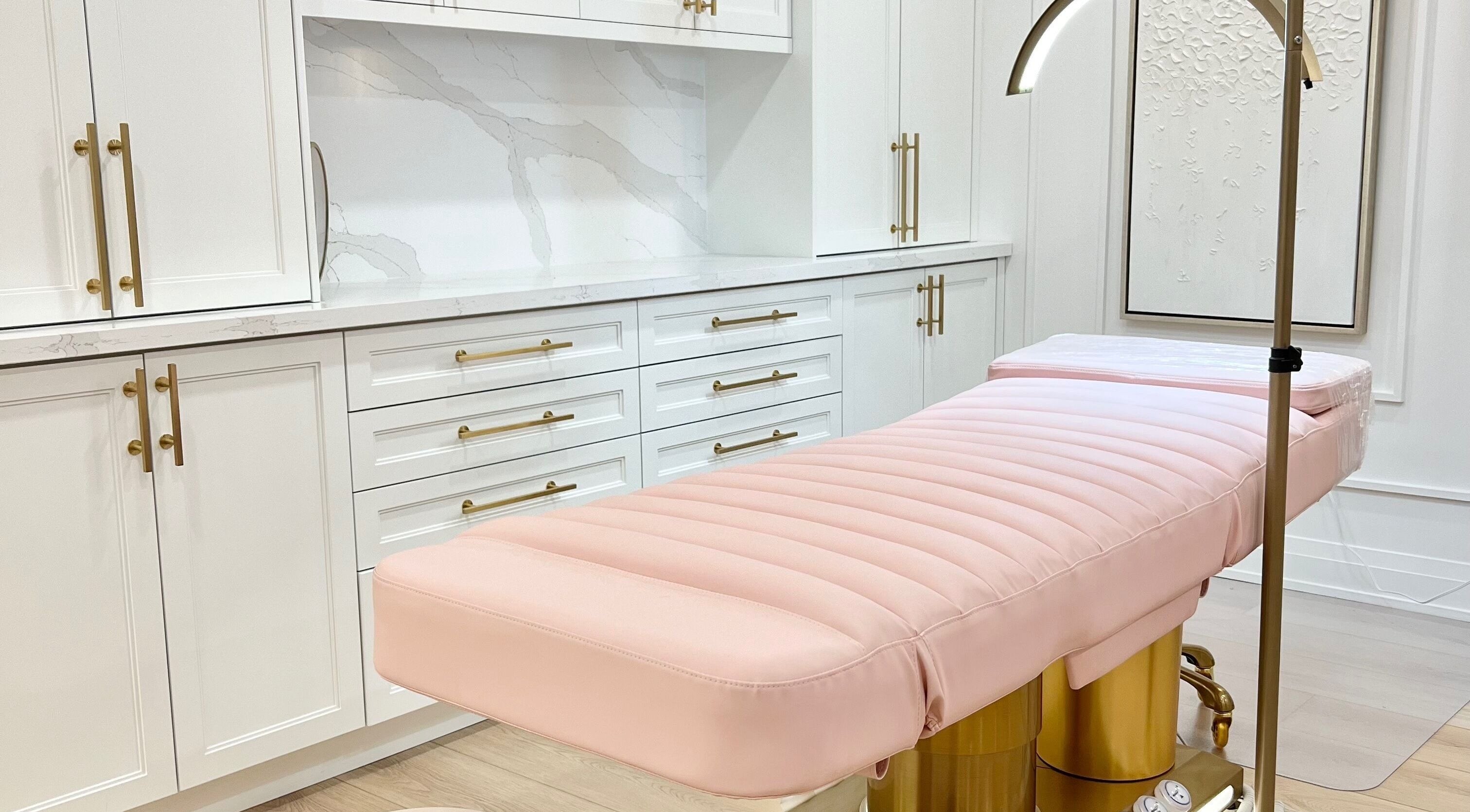 Elegant treatment room at Lash Layer and Brow Boutique, Pickering, Ontario, CA with plush pink bed and gold accents.