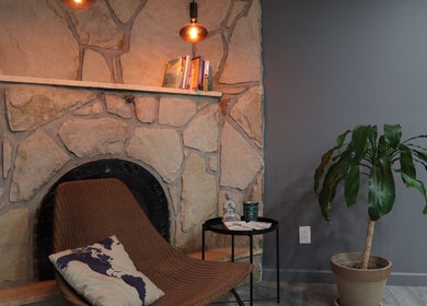 Cozy lounge spot at The Spot in Montréal, Québec, CA with stone fireplace and lush plant decor.
