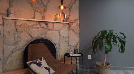 Cozy lounge spot at The Spot in Montréal, Québec, CA with stone fireplace and lush plant decor.