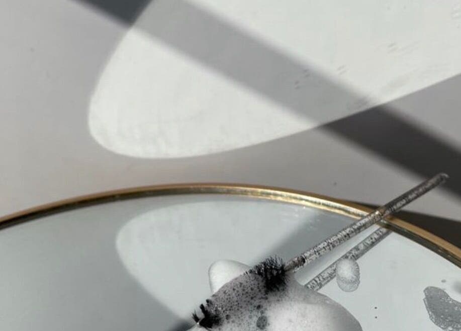 Close-up of a mirror with soapy bubbles and lash brush at sooAesthetic, Brockton, Massachusetts, US.