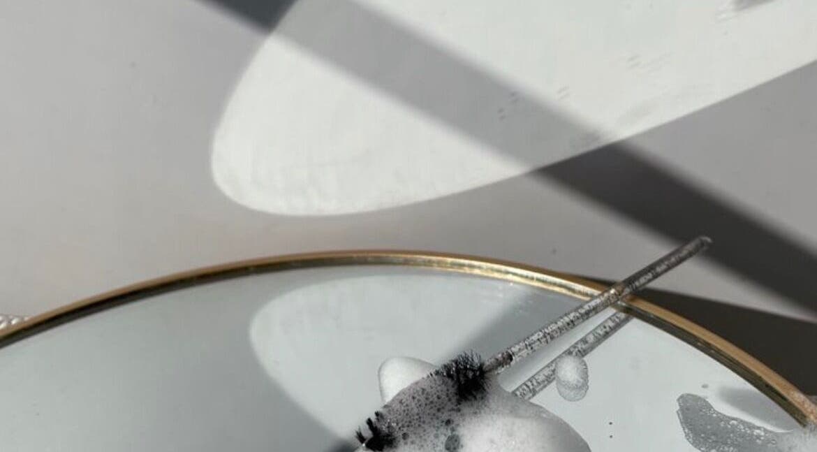 Close-up of a mirror with soapy bubbles and lash brush at sooAesthetic, Brockton, Massachusetts, US.