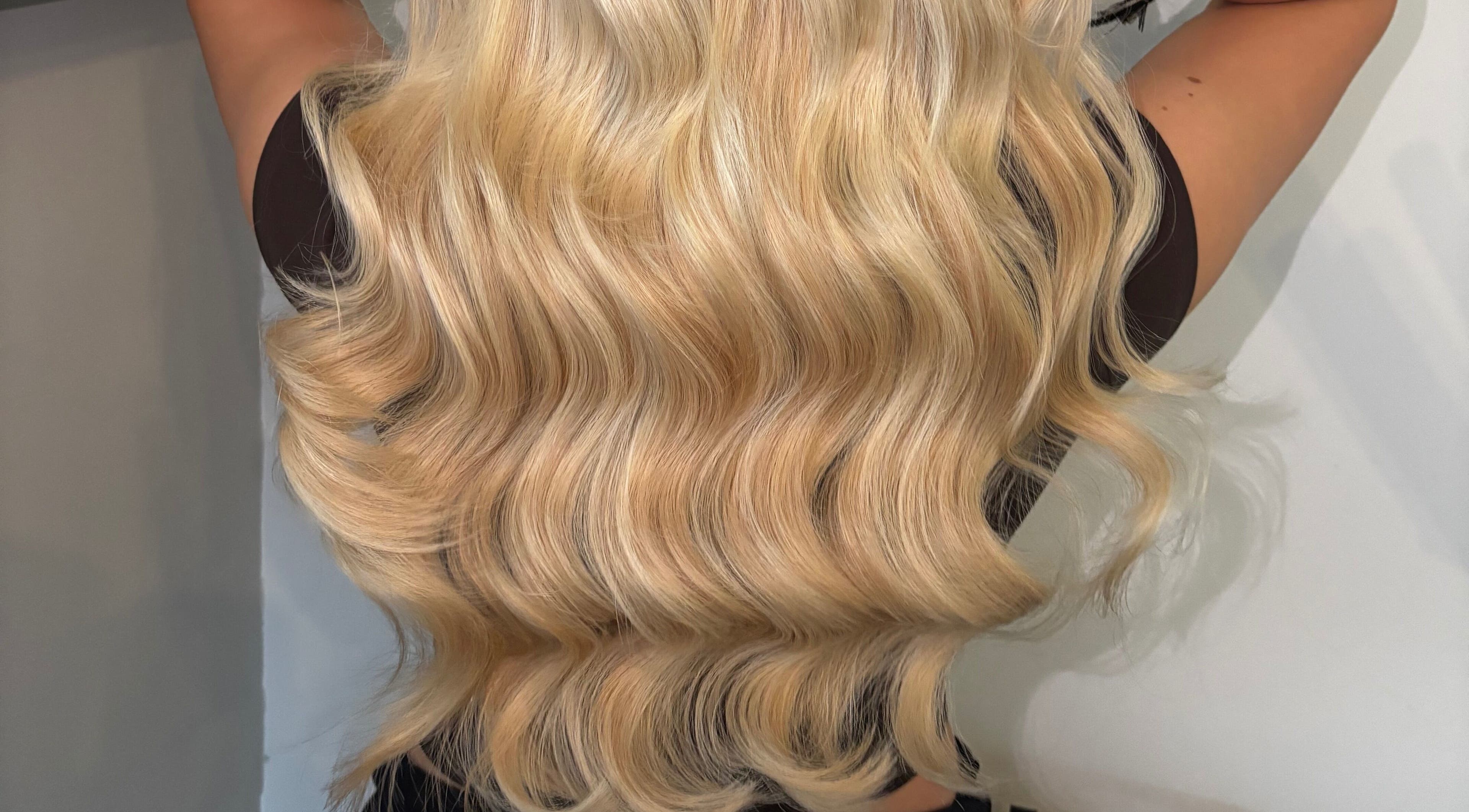 Lustrous blonde hair extensions styled in waves at GMR Extensions, Northampton, England, GB.