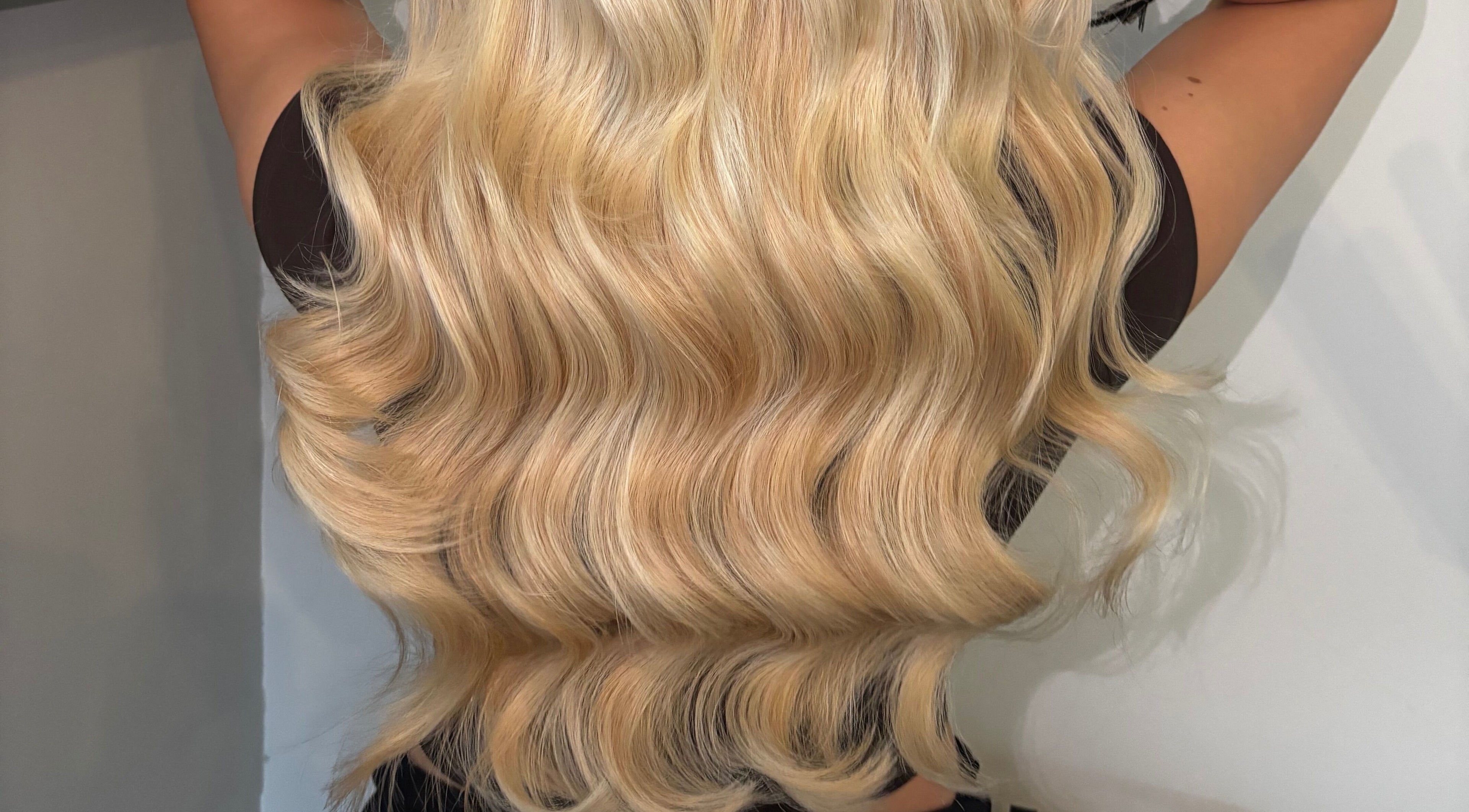 Lustrous blonde hair extensions styled in waves at GMR Extensions, Northampton, England, GB.