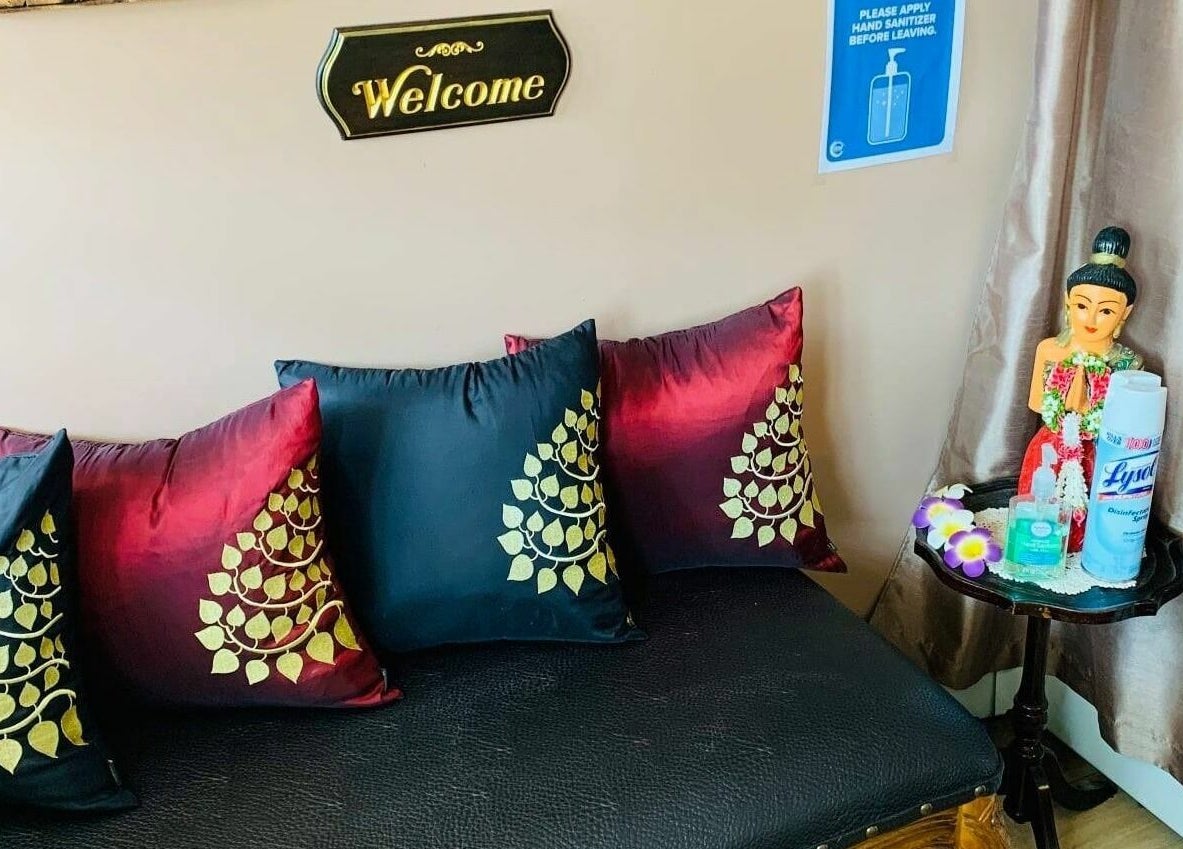 Inviting seating area at Thai Villa Spa, Newton, Massachusetts, US with decorative pillows and welcoming sign.