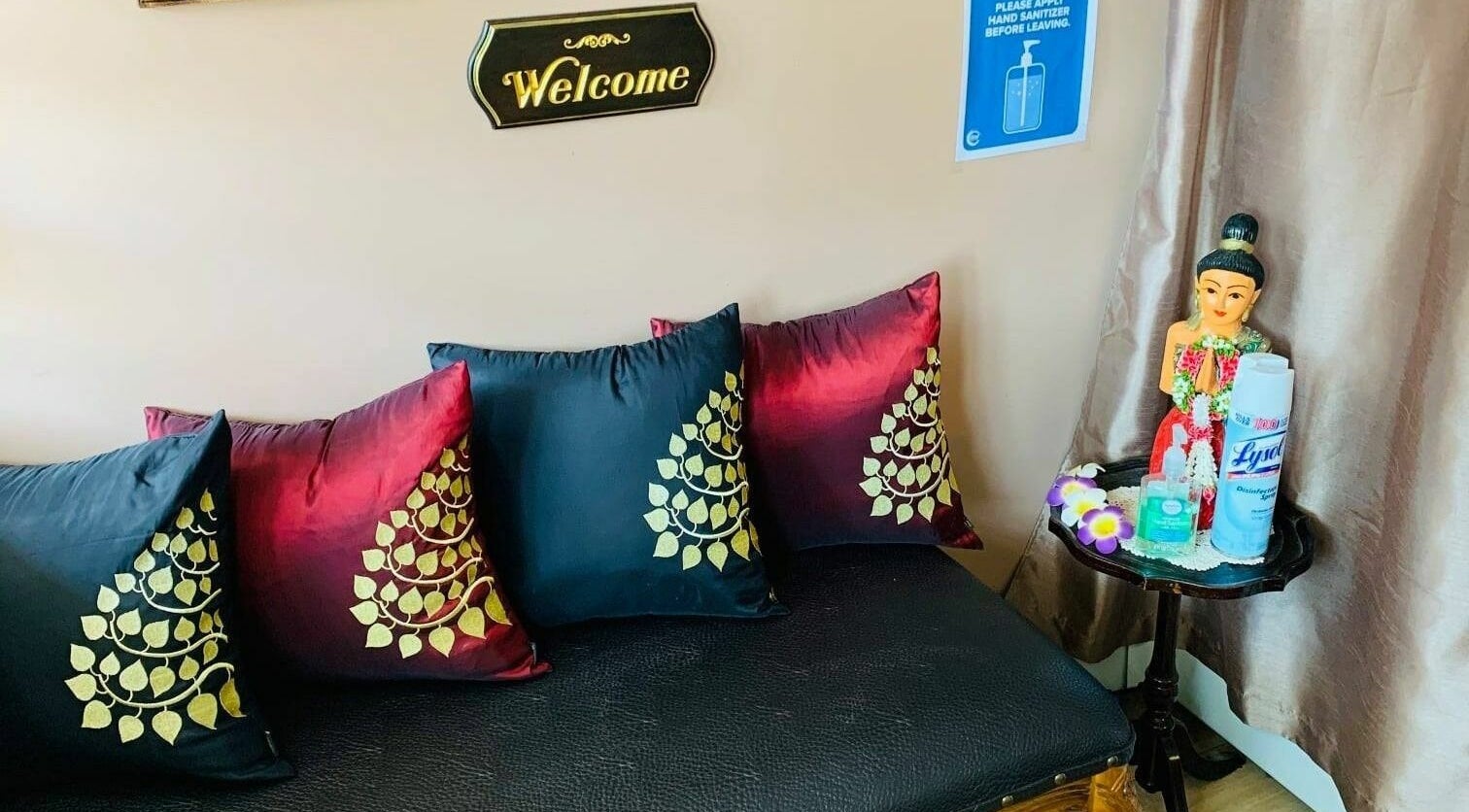 Inviting seating area at Thai Villa Spa, Newton, Massachusetts, US with decorative pillows and welcoming sign.