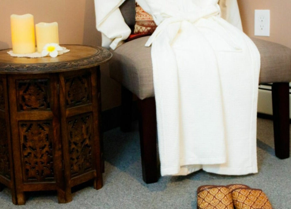 Cozy relaxation corner at Thai Villa Spa, featuring a plush robe and candles, Newton, Massachusetts, US.