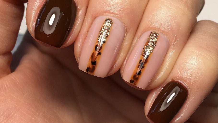 Elegant nail design with brown polish and gold accents at Rebecca Davies Beauty, Kenfig Hill, Wales, GB.