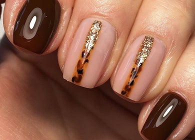 Elegant nail design with brown polish and gold accents at Rebecca Davies Beauty, Kenfig Hill, Wales, GB.