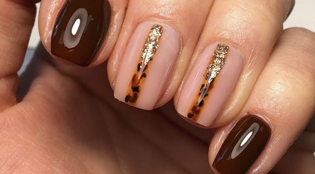 Elegant nail design with brown polish and gold accents at Rebecca Davies Beauty, Kenfig Hill, Wales, GB.