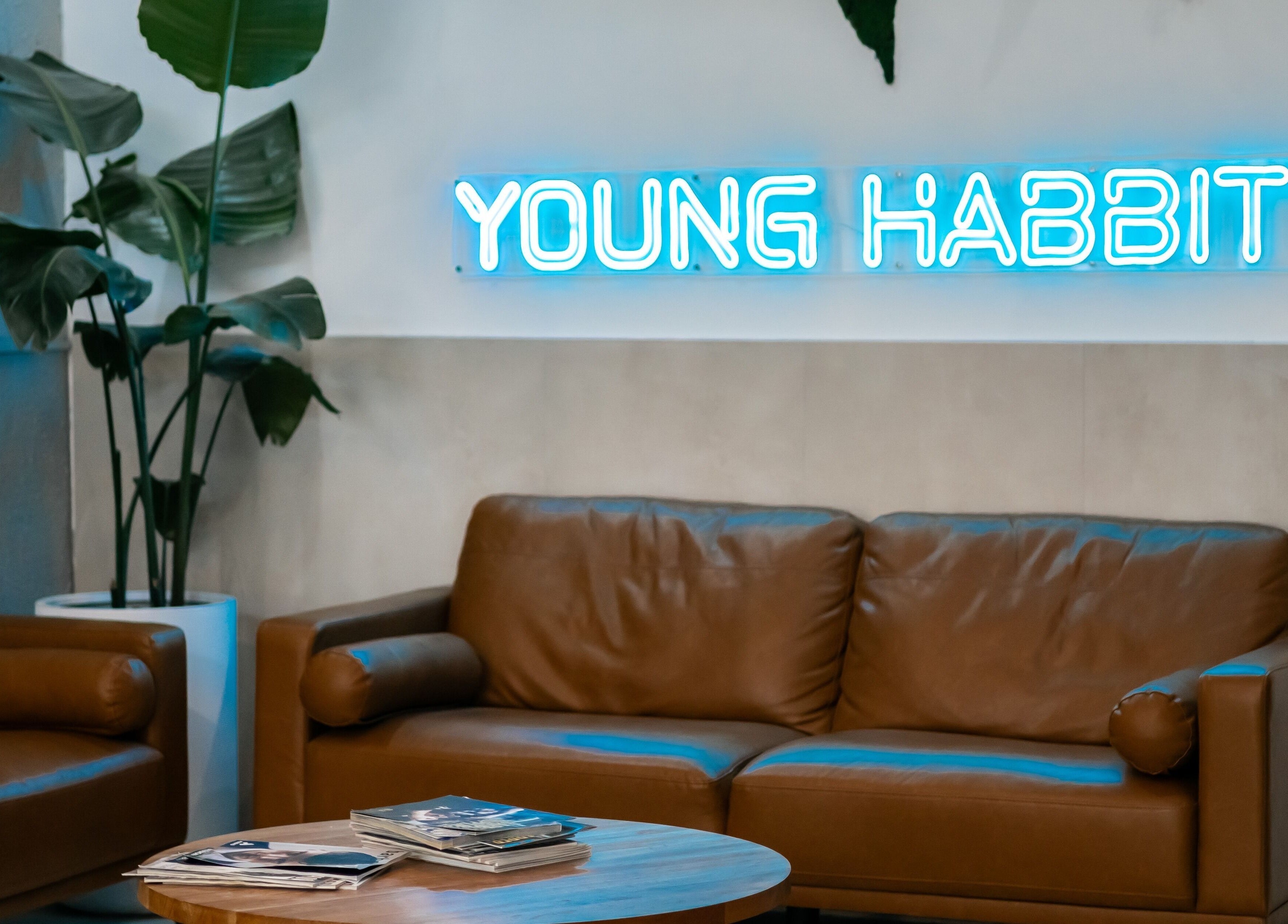 Cozy lounge at Young Habbitt Barbers - Werribee, Melbourne, Victoria, AU featuring leather sofas and neon sign.