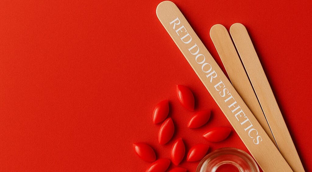Red Door Esthetics branding with wooden tools in Leduc, Alberta, CA on vibrant red background.