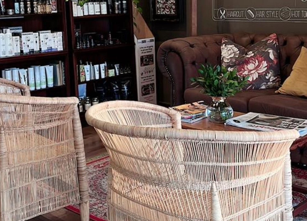 Welcoming seating area at Kuif & Baard Barbershop, Pretoria, Gauteng, ZA, with chairs, couch, and bookshelf.