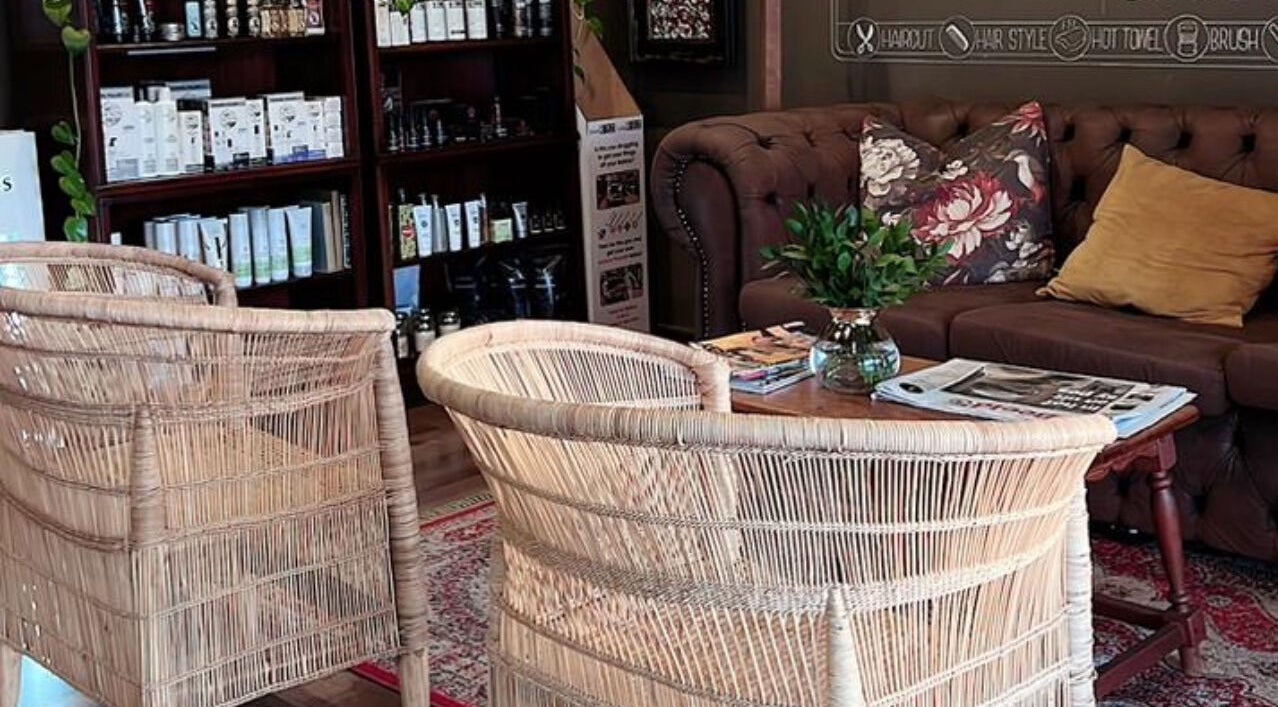 Welcoming seating area at Kuif & Baard Barbershop, Pretoria, Gauteng, ZA, with chairs, couch, and bookshelf.