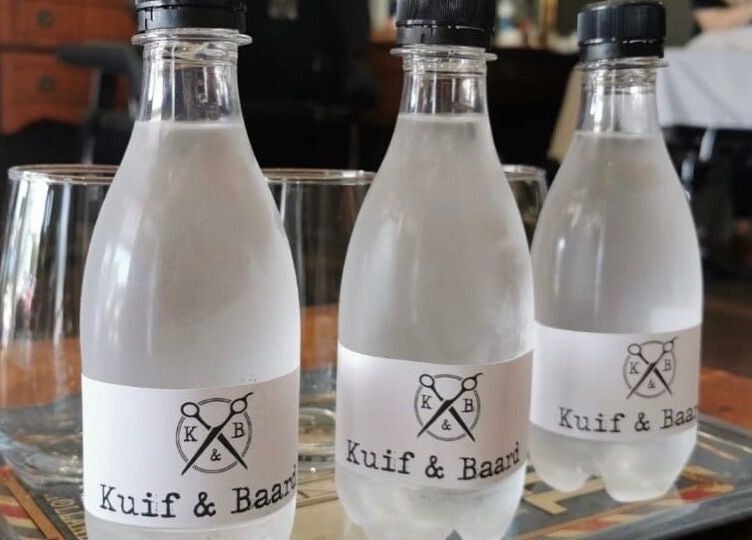 Bottled water with Kuif & Baard Barbershop logo at Pretoria, Gauteng, ZA, displayed on a tray.