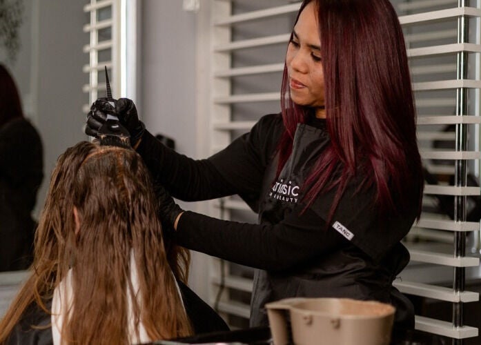 Stylist applying hair color at Intrinsic Hair & Beauty, Cape Town, Western Cape, ZA.