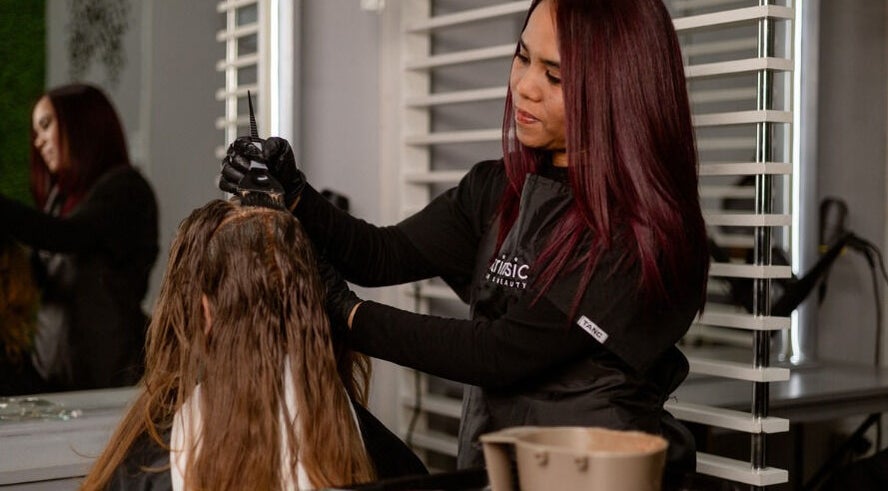 Stylist applying hair color at Intrinsic Hair & Beauty, Cape Town, Western Cape, ZA.