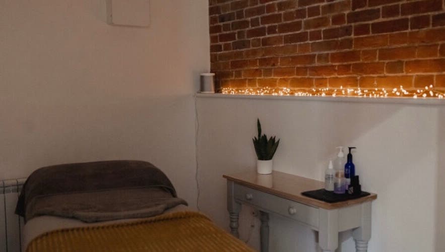Cozy treatment room at The Barn Beauty Rooms, Norwich, England, GB with brick wall and ambient lighting.