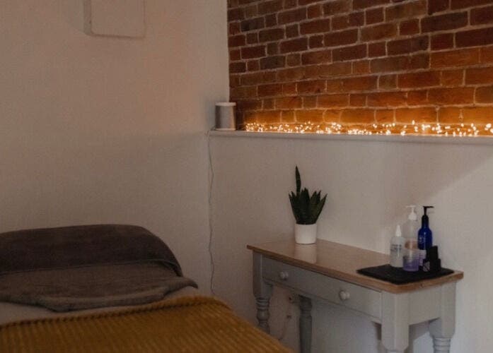 Cozy treatment room at The Barn Beauty Rooms, Norwich, England, GB with brick wall and ambient lighting.