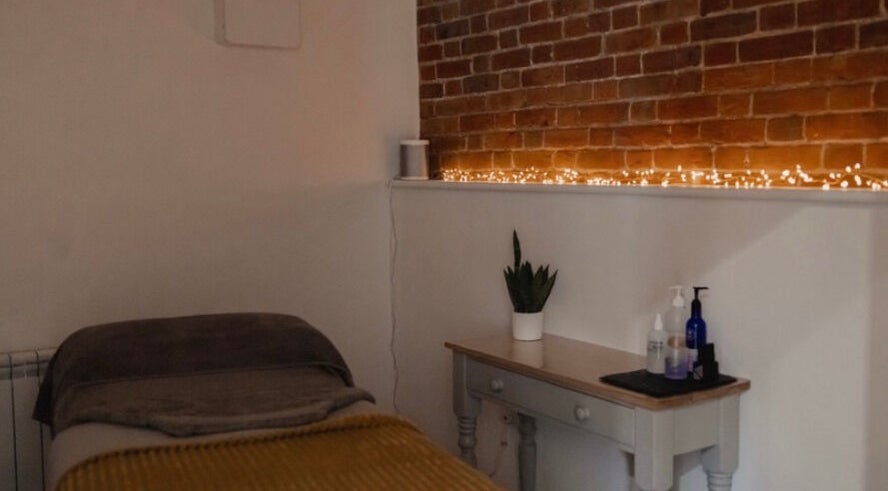 Cozy treatment room at The Barn Beauty Rooms, Norwich, England, GB with brick wall and ambient lighting.