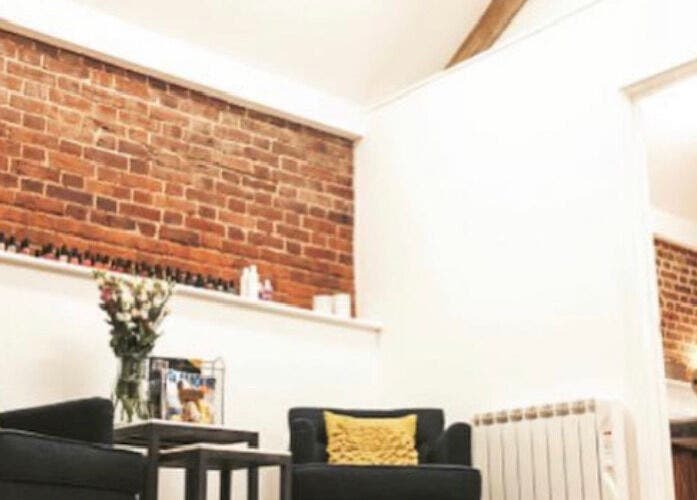 Cozy lounge area at The Barn Beauty Rooms, Norwich, England, GB, featuring exposed brick walls and plush seating.