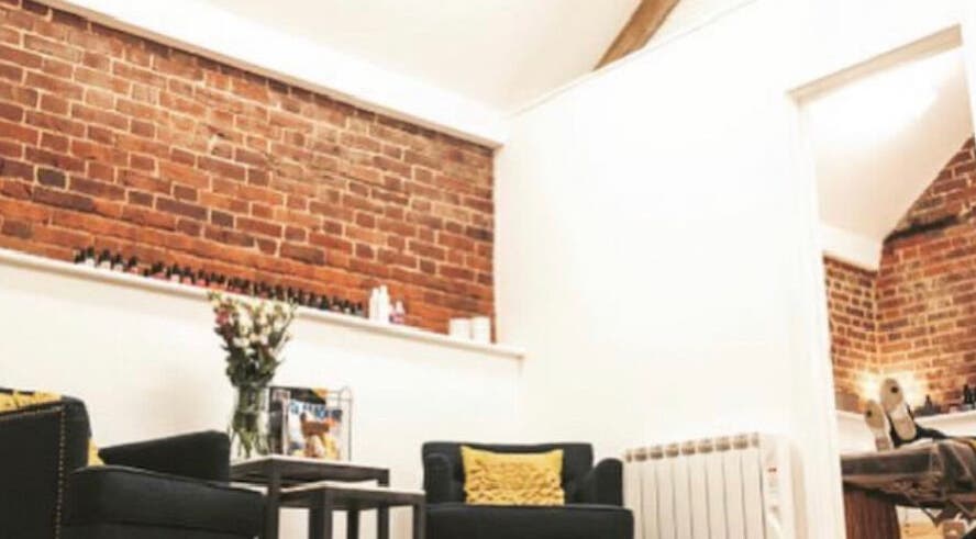 Cozy lounge area at The Barn Beauty Rooms, Norwich, England, GB, featuring exposed brick walls and plush seating.
