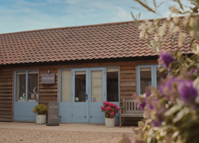 Charming exterior of The Barn Beauty Rooms, Norwich, England, GB, showcasing rustic design and vibrant flowers.