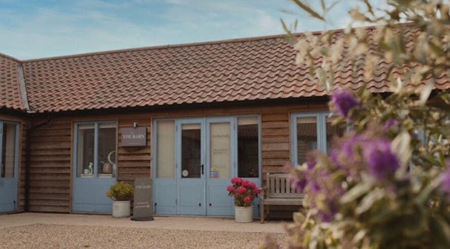 Charming exterior of The Barn Beauty Rooms, Norwich, England, GB, showcasing rustic design and vibrant flowers.