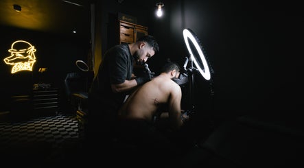 Tattoo artist working at BarberSmiths Tattoo Studio in London, England, GB with neon decor and professional setup.