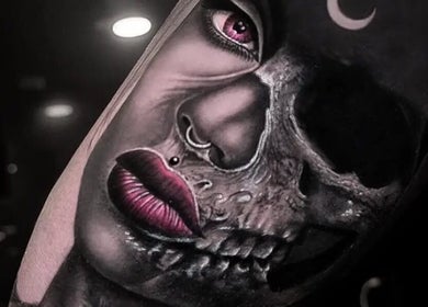 Detailed tattoo of a half-human, half-skull face at BarberSmiths Tattoo Studio, London, England, GB.